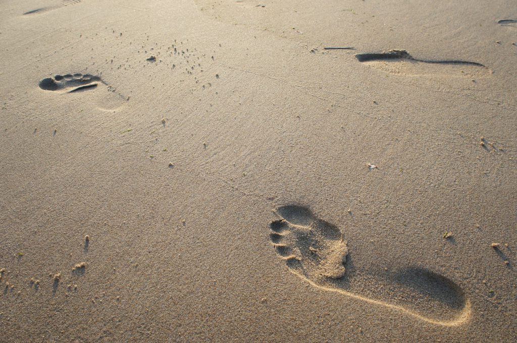Två fotspår i sand.