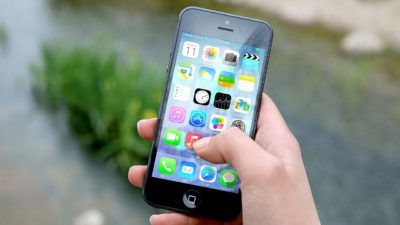 En person håller en smartphone i handen. På skärmen syns flera appar