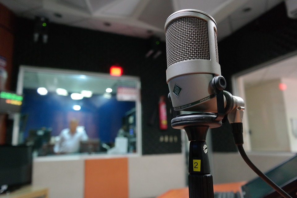En mikrofon med en radiostudio i bakgrunden