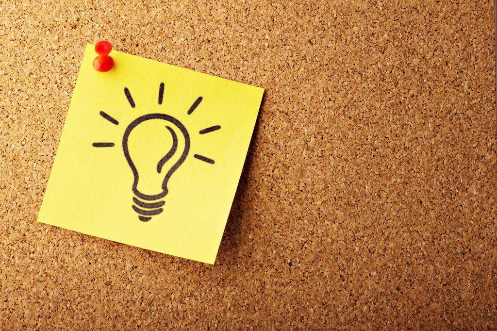 Bild på en post-it-lapp med en glödlampa som nålats upp på en tavla.