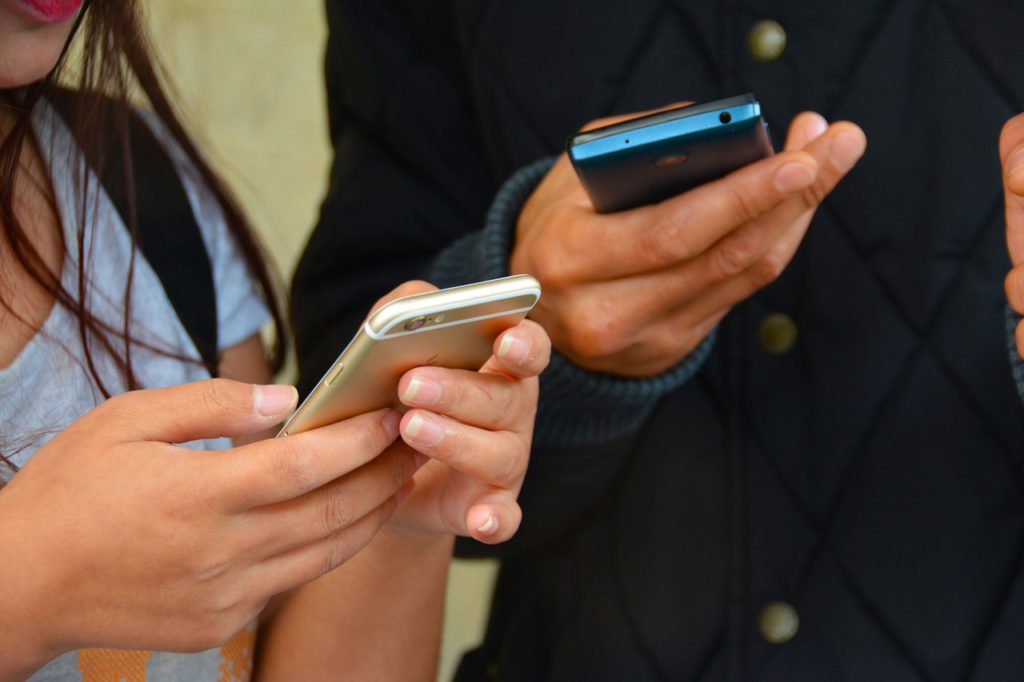Två personer som håller i varsinn smartphone